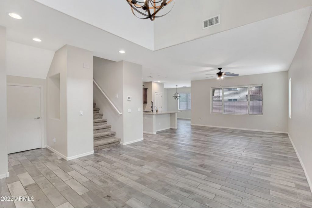 a wide angle of the same living room space with a wall removed for openness, new modern wood tile floors, new light fixtures and new paint