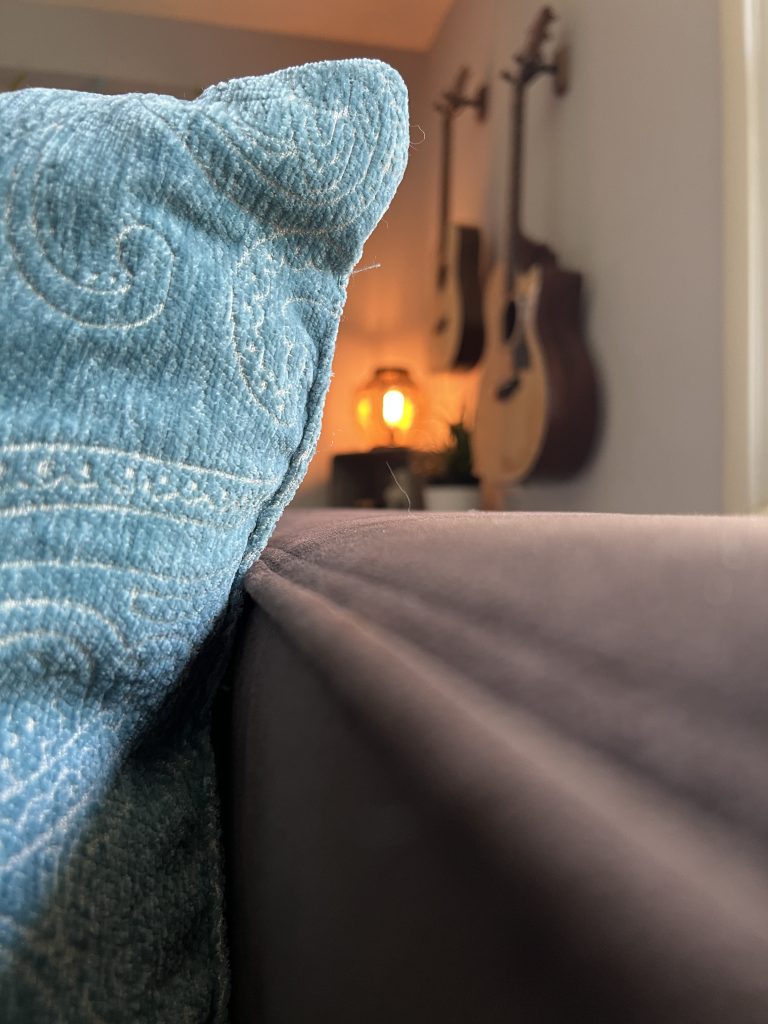 a closeup shot of a blue pillow with guitars hanging on the wall in the background
