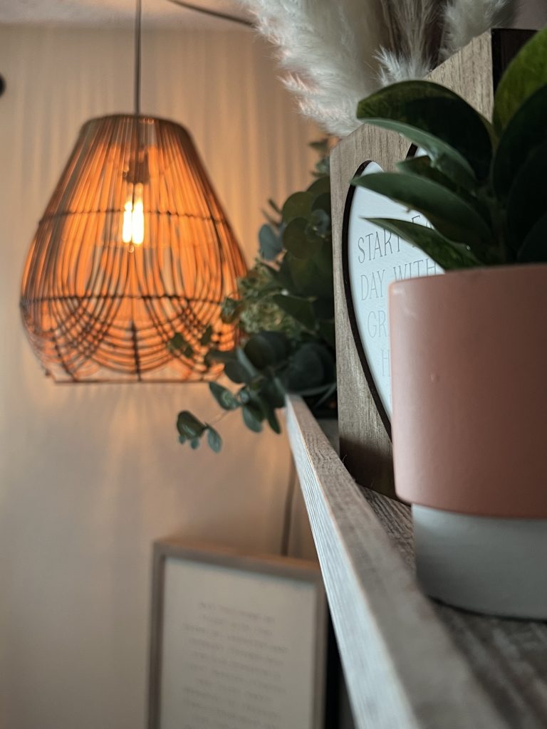 a sideways look at a floating shelf with beautiful decorations and hanging lights in the background