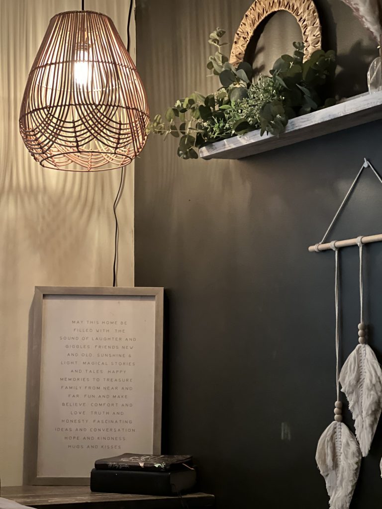 a closeup of a floating shelf underneath a pendant light and with a decorative sign perched on a table