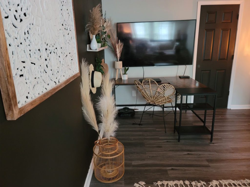 a bedroom desk setup with a large tv monitor and a vase with feathers