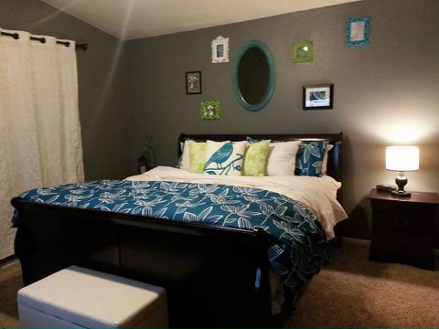 a painted bedroom with bright decorative frames on a wall above the bed, and bright bedding and accessories